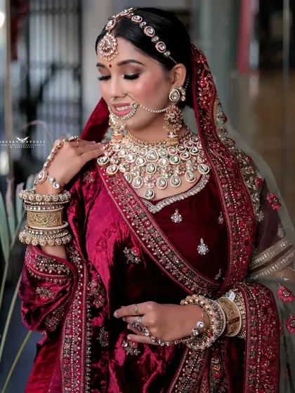 A shot capturing the bride's gentle expression, with a focus on the detailed makeup and heavy kundan necklace.