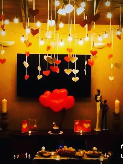 I can create a romantic focal point anywhere in your home. This intimate setup features a console table decorated with hanging hearts, warm string lights, candles, and heart-shaped balloons for a small but impactful surprise.