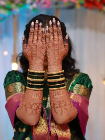 A classic bridal pose, with the bride hiding her face behind her beautifully adorned hands. The back-hand design and the rich stain are on full display.