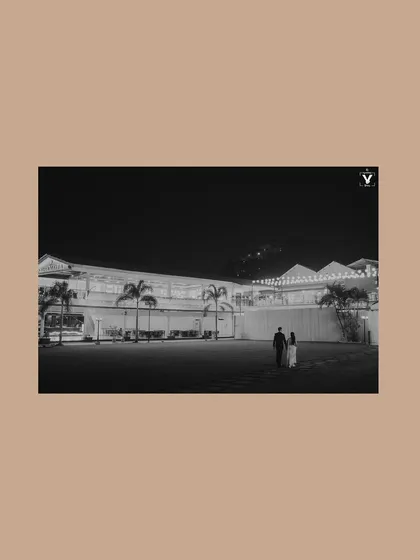 A minimalist black and white shot of a couple walking across a lawn at night. The vast empty space and the distant building create a cinematic and slightly mysterious feel.