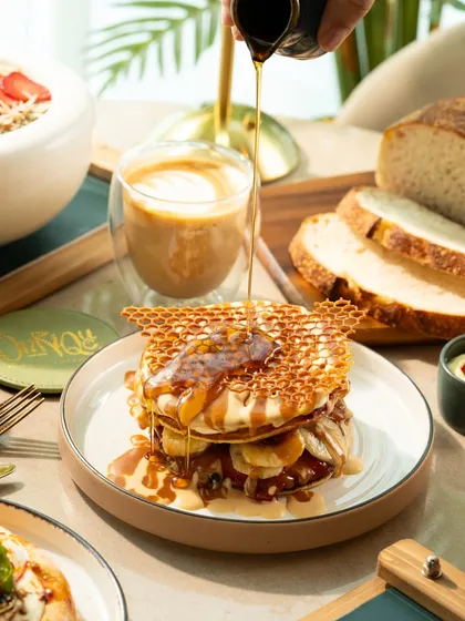 The perfect syrup pour over banana pancakes with a honeycomb wafer. This action shot is dynamic and makes the dish look extra delicious.