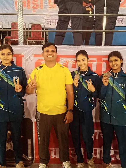 A coach celebrates with our victorious girls team. Their smiles and victory signs capture the joy of a hard fought win at the national level.