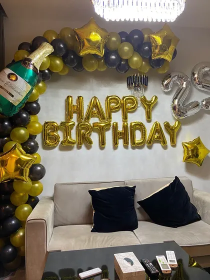 I offer stylish and modern decoration setups for adult birthdays at home. This 25th birthday arrangement includes a chic black and gold balloon arch with a champagne bottle foil balloon, star accents, and large foil letters and numbers.