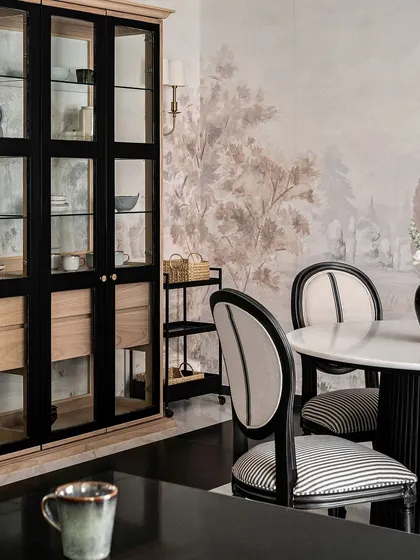 A detail shot of the dining area, highlighting the elegant striped upholstery on the classic-style dining chairs and the custom black and oak glass-front cabinet.