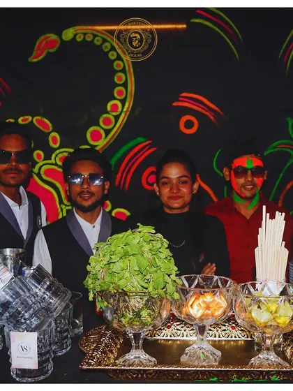 Our team posing in front of a cool neon-painted wall. We are the mixology masters who bring the magic and create unforgettable nights.