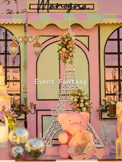A chic Parisian backdrop with an Eiffel Tower prop and a pink teddy bear.