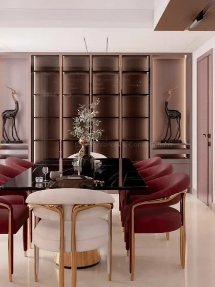 An elegant dining space designed for memorable gatherings. The combination of a black marble tabletop, plush velvet chairs with brass accents, and custom back-lit cabinetry creates an atmosphere of sophisticated luxury.