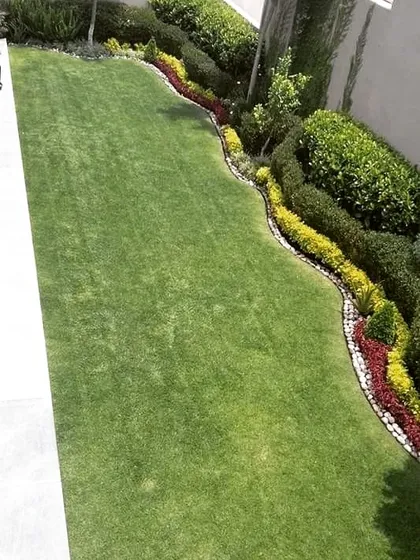 An aerial view of a lawn with a gracefully curving border of colorful, low-lying shrubs. This design technique adds movement and visual interest to a simple grass area.
