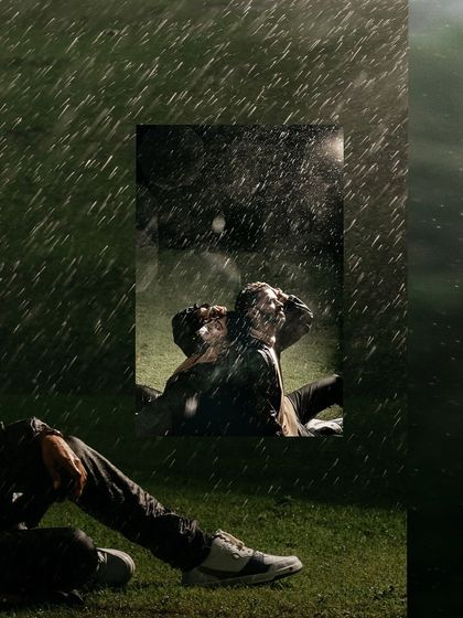 A creative and moody shot of a couple relaxing in a field during a downpour, capturing a unique and artistic pre-wedding moment.