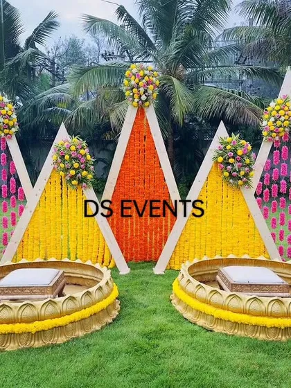 For this outdoor Haldi ceremony, I designed a vibrant setup using A-frame backdrops with marigold and tuberose flower hangings. The custom-made lotus-shaped urlis for the seating add a unique and traditional touch, making it perfect for photos.