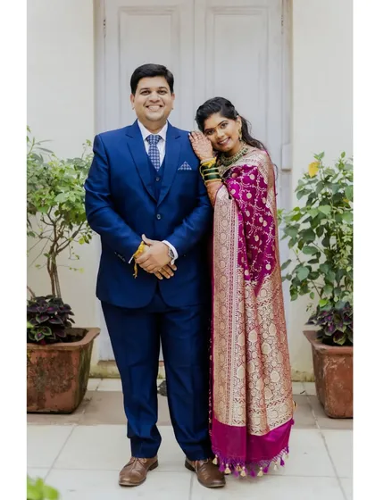 A full-length portrait of Alok and Shilpa. The bride's rich magenta Paithani saree and the groom's classic blue suit make a beautiful combination.
