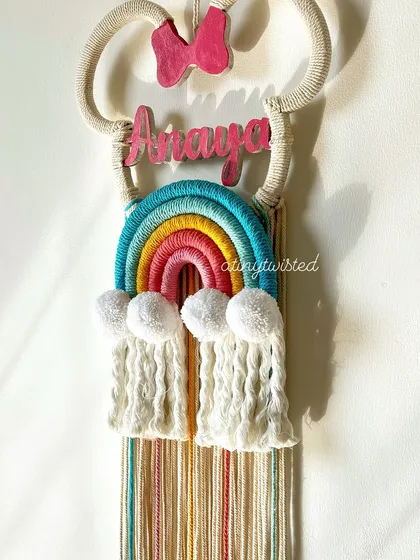 A close-up shot of the 'Anaya' Minnie Mouse nameplate, showing the detail on the hand-painted name, the texture of the rainbow, and the fluffy pom-pom clouds.