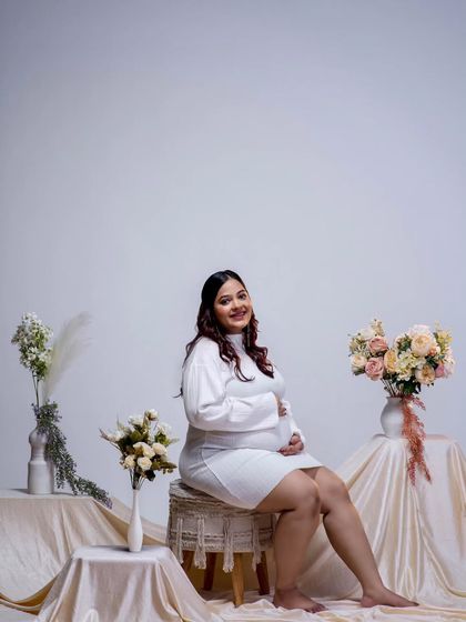 A beautiful, confident solo portrait of the mother-to-be. Seated comfortably, her happy expression and the elegant studio setup create a timeless and joyful image.