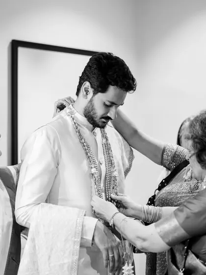 The getting ready process is full of special moments. Here, Akshay's mom and aunt help him with his outfit. This black and white photo captures the love and support surrounding the groom.