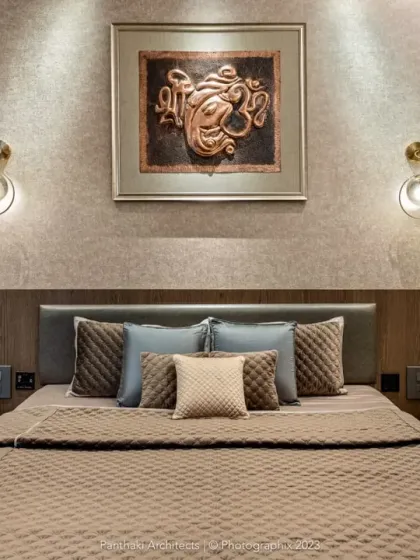 A close-up of a master bedroom where warm wood paneling creates a cozy backdrop. The space is personalized with elegant wall sconces and a meaningful piece of art, making it a true sanctuary.