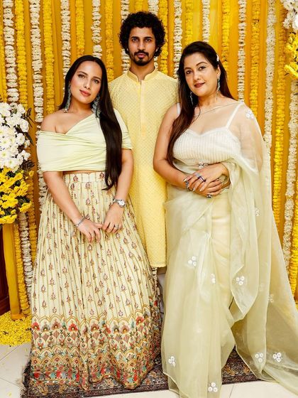 The groom's mate in the spotlight. A handsome guest in a yellow kurta stands with the bride's family, showcasing a perfect look for a pre-wedding function.