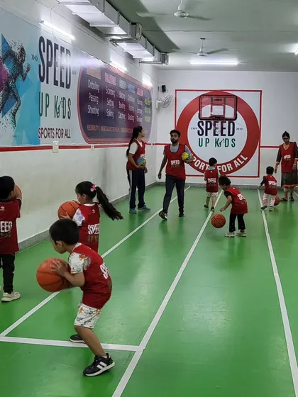 A wide shot of our basketball skills session. You can see multiple kids practicing their dribbling at their own pace in a structured environment.
