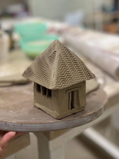 We encourage students to bring their ideas to life, like this charming miniature house sculpted from clay.