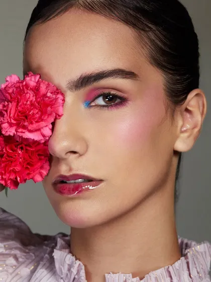 A playful pop of color with pink and blue eyeshadow, complemented by a fresh pink carnation.