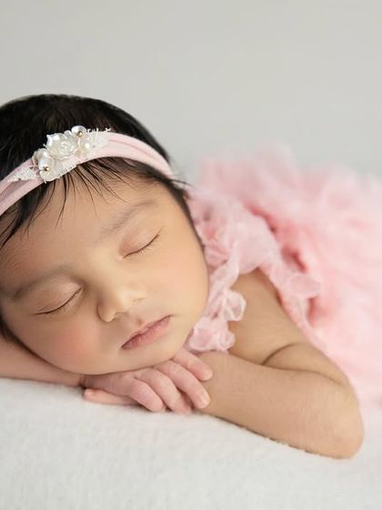 A close up of the side pose, focusing on the baby's serene, sleeping face. The simple headband adds a delicate touch.