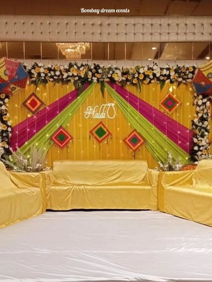A full view of a banquet hall Haldi stage, showing how I use colorful drapes and a neon sign to create a grand setup.