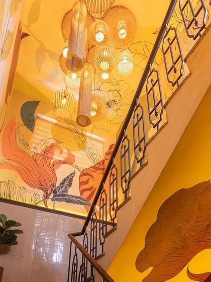 Looking up the transformed staircase, the interplay of the mural, the custom railing, and the cluster of lights creates a dynamic and visually rich experience.
