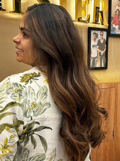 A side view of a client's hair with global highlights. The soft waves and blended tones create a beautiful, multi-dimensional look that is full of life.