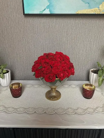 A beautiful floral centerpiece of red roses in a glass bowl, perfect for adding a touch of elegance to a console table or reception area during a home event.