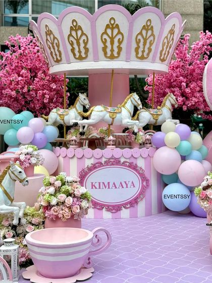 The central carousel prop with its beautiful horses, surrounded by pastel balloons and floral arrangements.