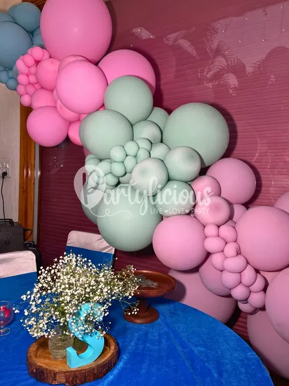 A pastel balloon garland cascades beautifully next to a dining table set for a party, seamlessly integrating the decor with the dining experience.