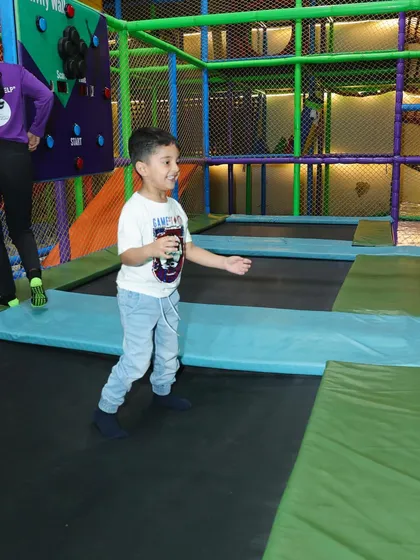A young boy enjoying the trampoline section, with our attentive staff member nearby.