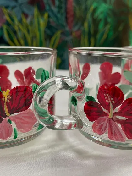 A set of glass cups painted with red hibiscus flowers, perfect for enjoying a cup of tea on a rainy day.