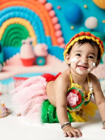 Look at that happy, messy face! Our cake smash sessions are all about pure joy and celebration. We create colorful, fun backdrops like this rainbow theme to make your baby's first birthday shoot unforgettable.