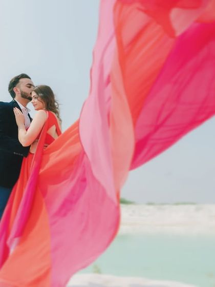 A close-up, artistic shot from a pre-wedding session, with the groom kissing the bride's forehead. The flowing fabric of the gown creates a beautiful, soft frame, highlighting the romance of the moment.