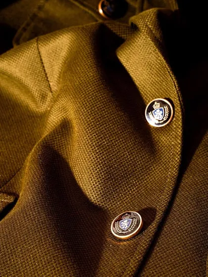 A close-up of the custom buttons on our olive green coat. Even our lightweight pieces feature luxurious, high-quality details.