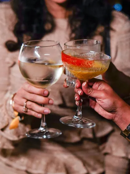 Guests toasting with glasses of white wine and cocktails, celebrating a special moment.