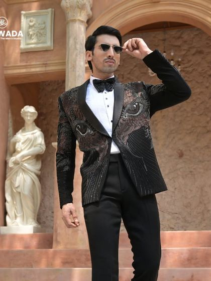The eye-motif tuxedo in a full-length pose, showing how the design creates a powerful and modern aesthetic. Paired with sunglasses, it's the epitome of cool confidence.