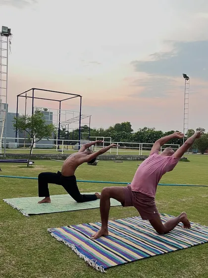 In a beautiful outdoor setting, two movers practice a low lunge variation (Anjaneyasana). This pose is excellent for opening the hips and stretching the chest and shoulders.