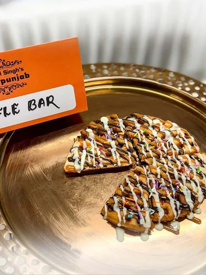 A freshly made waffle from our live Waffle Bar, drizzled with chocolate, white chocolate, and sprinkles. It's a sweet, crispy, and utterly irresistible treat.