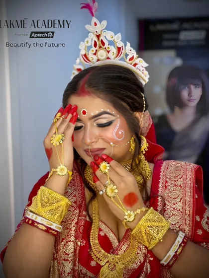 A beautiful student-created Bengali bridal look. The focus is on the traditional headpiece (mukut) and the classic red and gold jewelry, showcasing a complete and authentic style.
