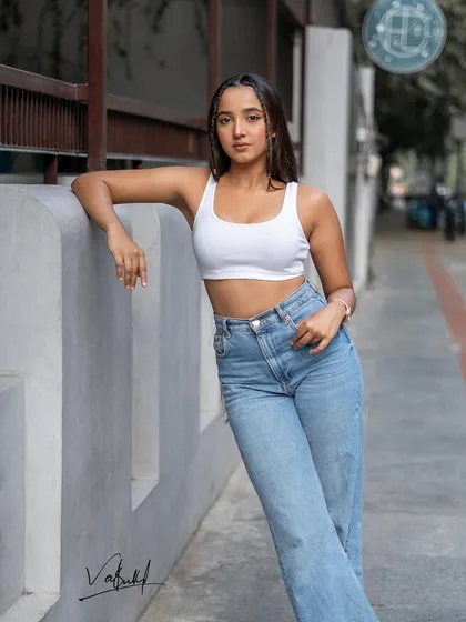 A classic street style pose, leaning against a concrete wall. The clean lines of the architecture contrast with the relaxed outfit, creating a balanced and modern fashion portrait.