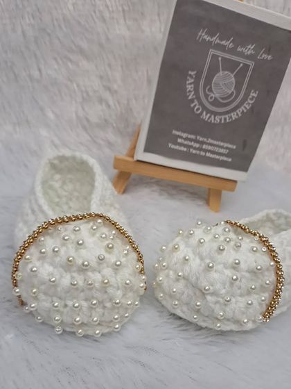 These extra-special white booties feature a strap made of sparkling gold-colored stones and are covered in delicate pearls.
