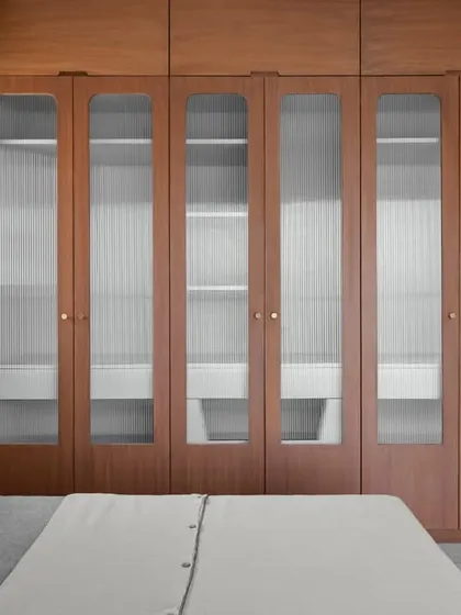 The wardrobe in this retro-inspired bedroom features fluted glass doors, adding texture and a touch of vintage charm. The design seamlessly integrates storage into the room's overall aesthetic.