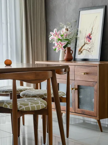 A low-height sideboard in the dining area, featuring fluted glass doors and a warm wood finish, perfect for storing dinnerware.