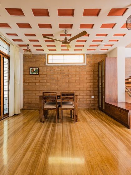 The dining and living area in Santosh and Deepali's home, featuring a filler slab ceiling with terracotta pots. This technique reduces concrete usage and helps keep the interior cool, while the wooden flooring adds warmth to the space.