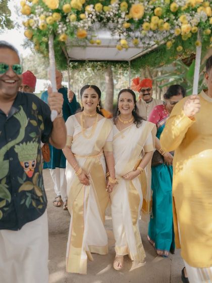 The bride's joyful procession. Pavitra, in her elegant Kerala saree, is escorted by her family, their smiles lighting up the path. This is a moment of pure family love and celebration.