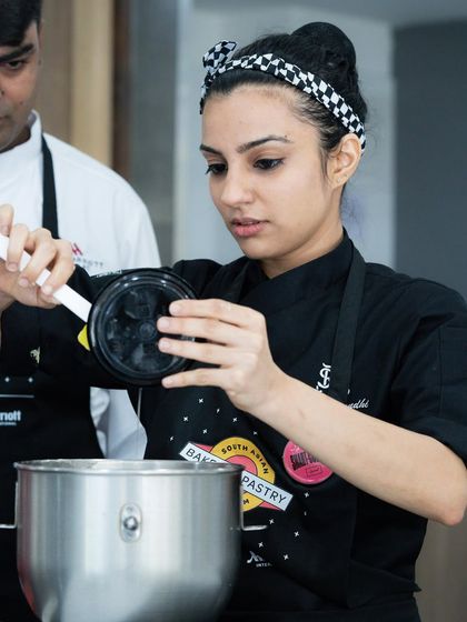 A participant at the Marriott symposium carefully measures ingredients for an advanced recipe.