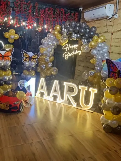 A full view of the butterfly-themed setup for Aaru, showing the balloon arch, pillars, and the ride-on car, all ready for the party.