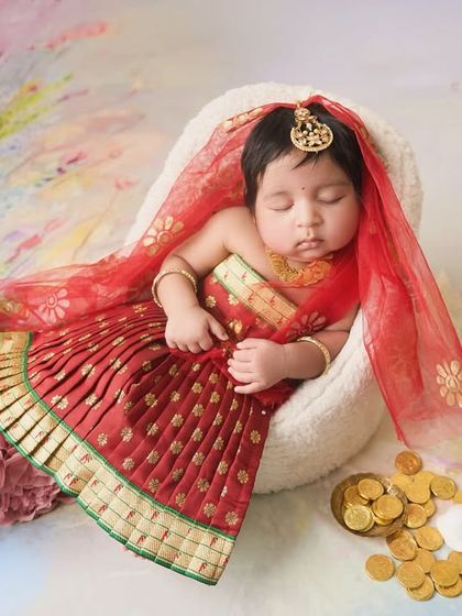 The complete setup for the little Lakshmi theme, with the baby surrounded by gold coins and pink flowers against a vibrant, painted backdrop.