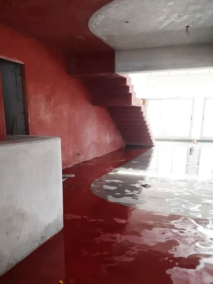 The curing process for the newly laid red oxide floor at the TAPMI Centre. The water reflects the raw concrete structure, creating a moment of poetic beauty on the construction site.
